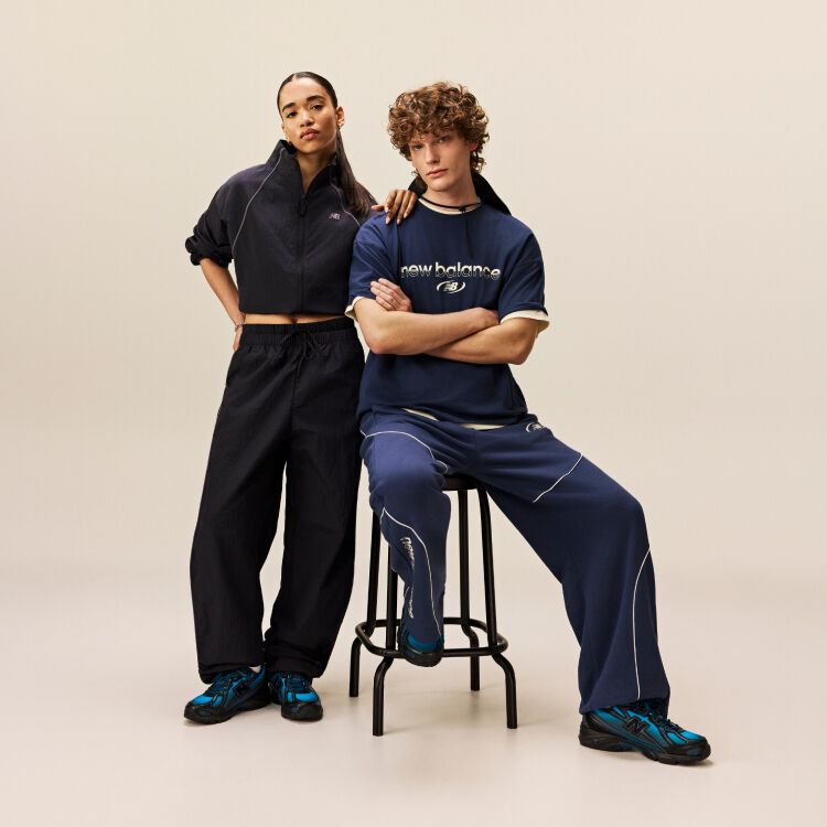  Man sitting down while woman is standing with her arm rested on his shoulder.
